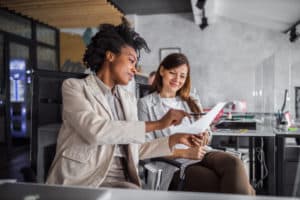 Motivated co- workers sitting next to each other and looking at some contracts.