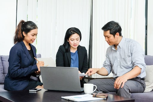 two female business women and one male working in front of computer