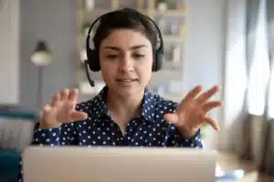 A woman with a headset interacting at her laptop