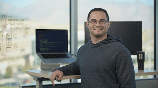 Male with Glasses in front of desk looking toward camera