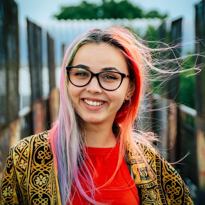 Woman with multicolor hair and glasses smiling