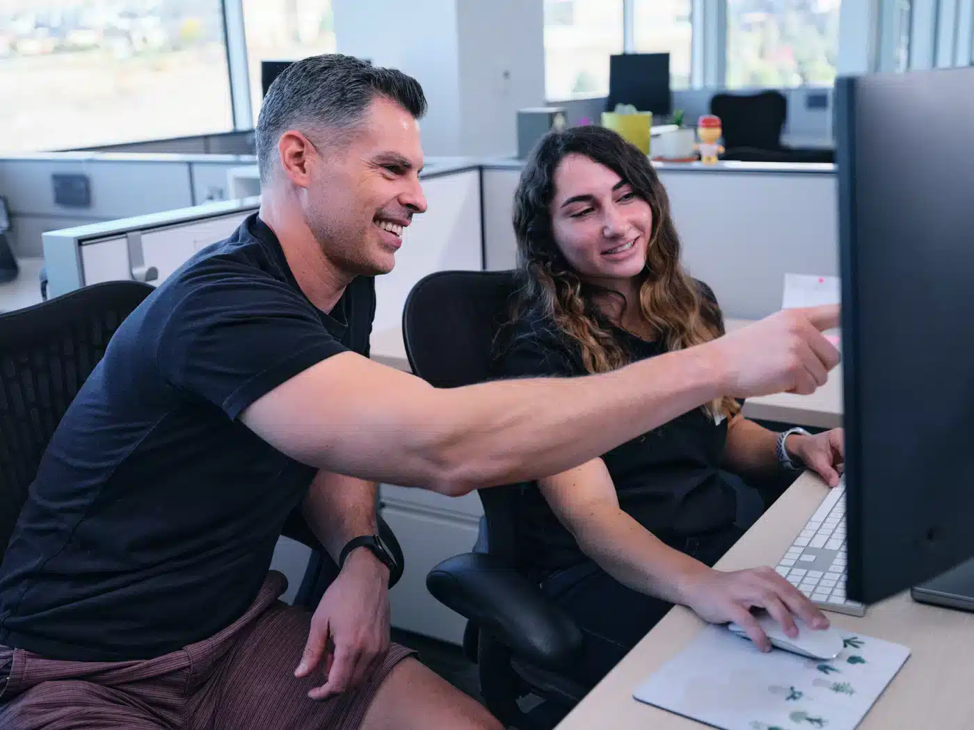 man and woman smiling looking at computer