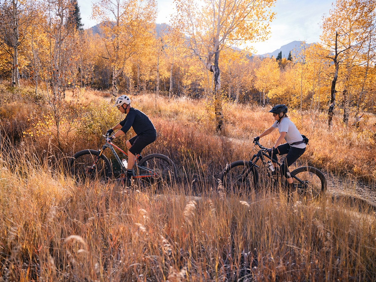 two people mountain biking on trail in the fall