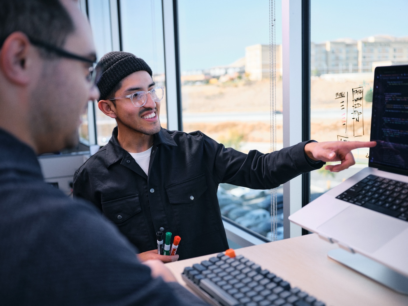 2 men pointing at computer